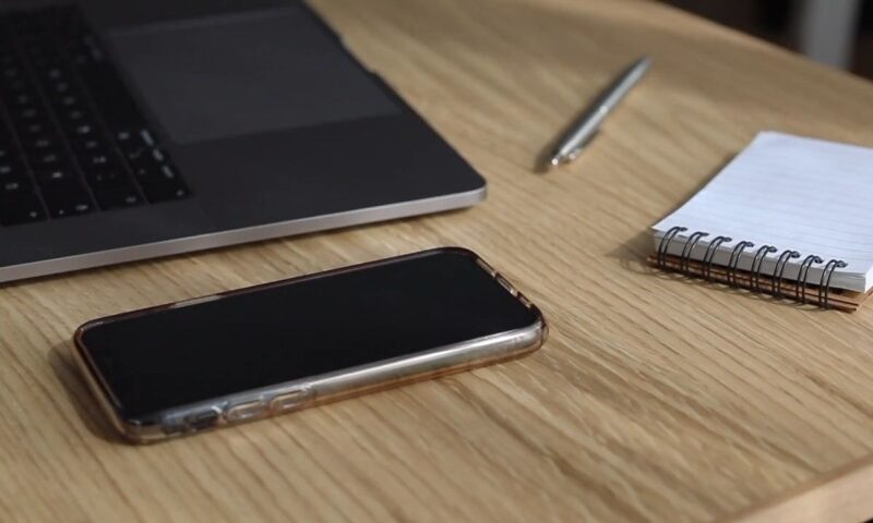 prikaz telefona na stolu sa laptopom, blokčićem i hemijskom