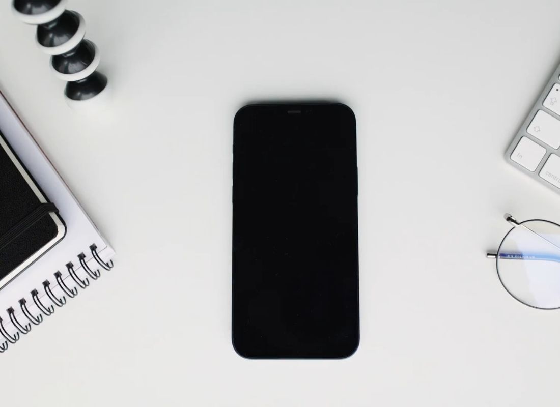 prikaz telefona, naočara za vid, sveske i tastature na belom stolu