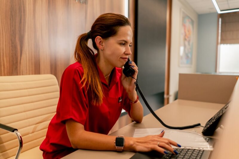 Žena razgovara telefonom i proverava dokumentaciju za prijavu na subvencije za samozapošljavanje u Novom Sadu